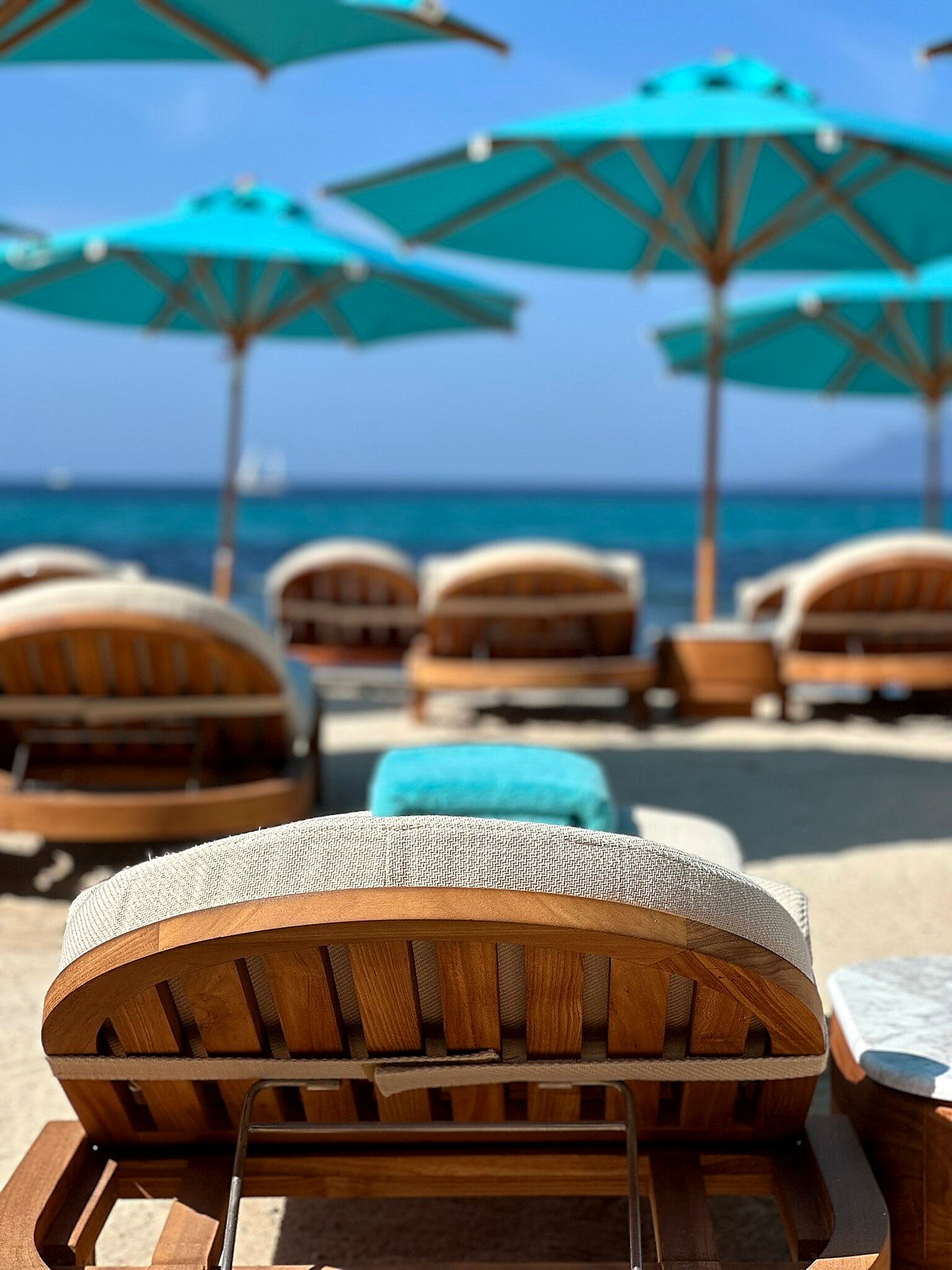 Turquoise parasols and teak day beds on the private beach