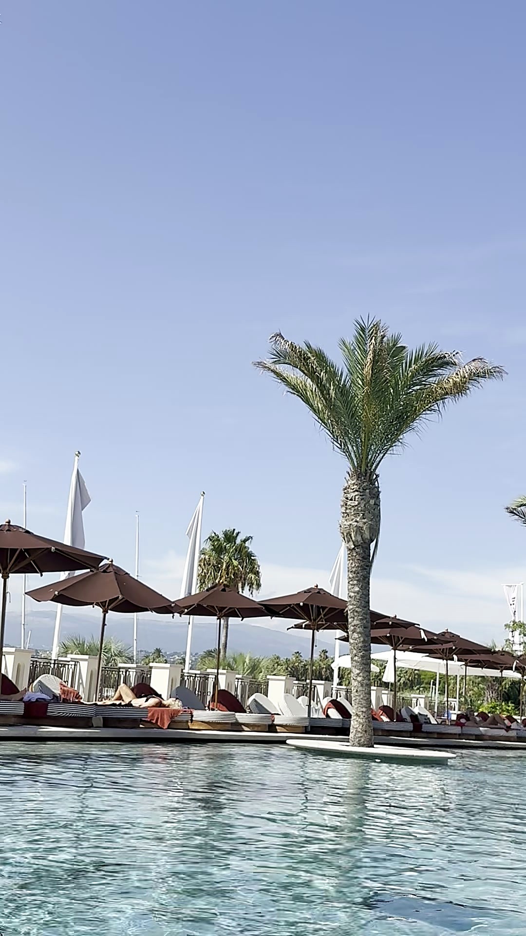 Palm Beach pool with brown parasols and mountain views